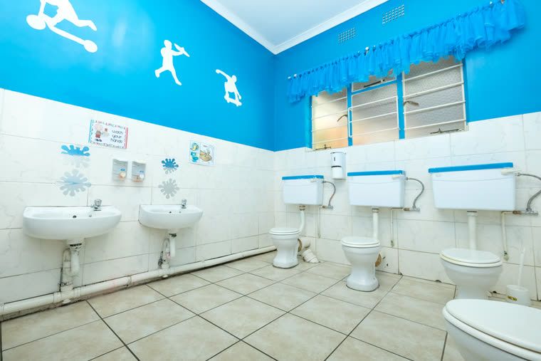 The boys' bathroom, with child-height basins and toilets and blue and white tiling