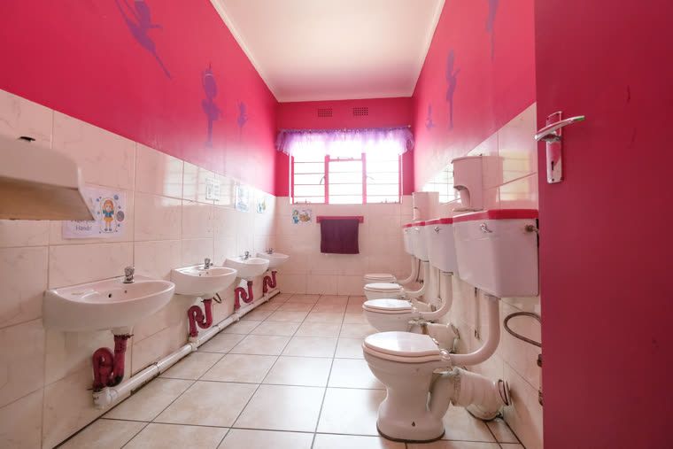 The girls' bathroom, with child-height basins and toilets and pink walls