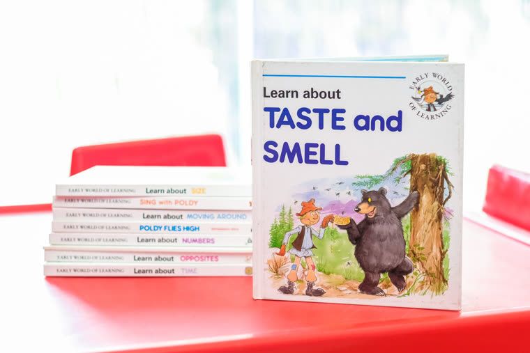 A picture book about taste and smell standing on a red table with others beside it