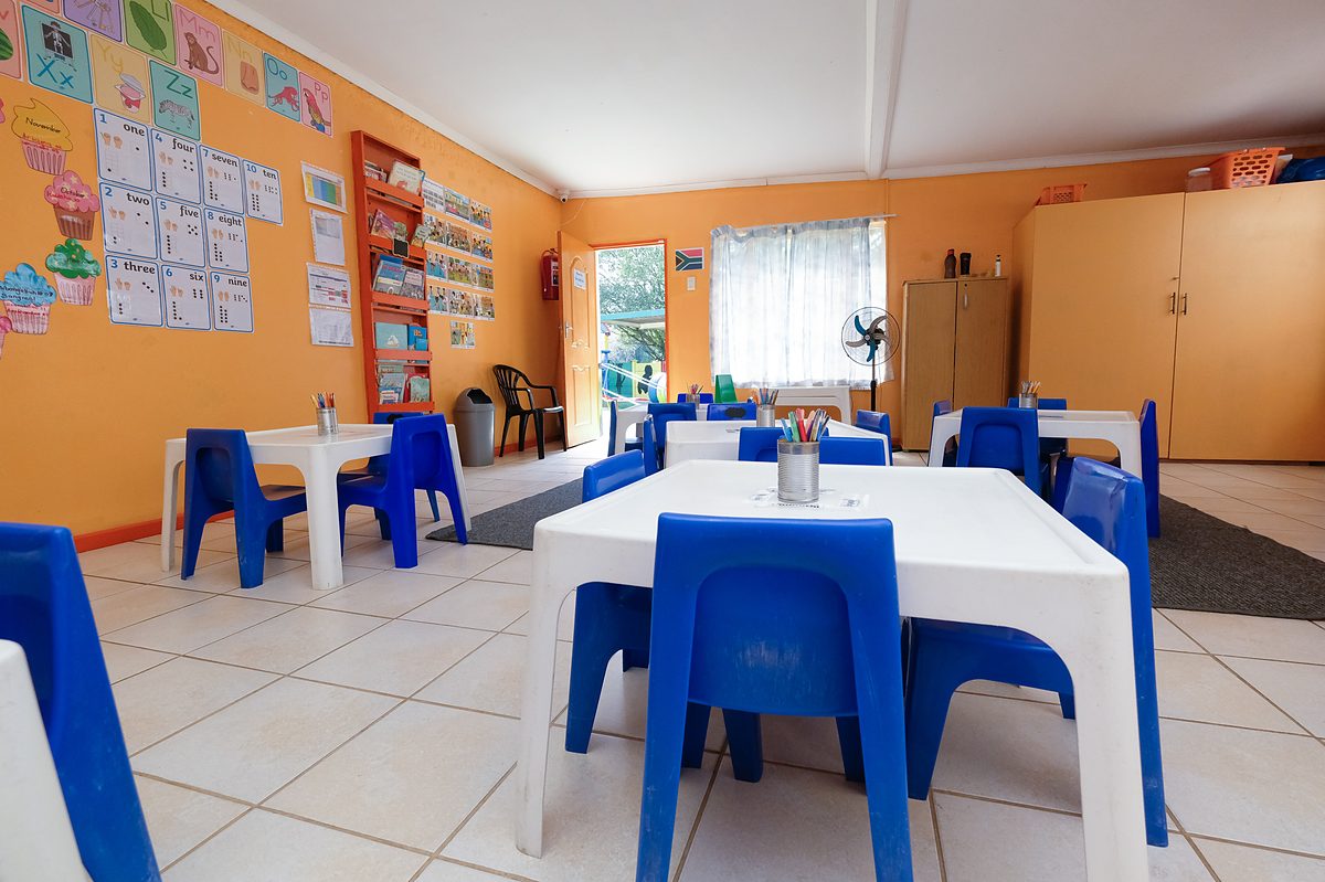 Orange Class: orange walls covered in charts, with white tables and blue chairs