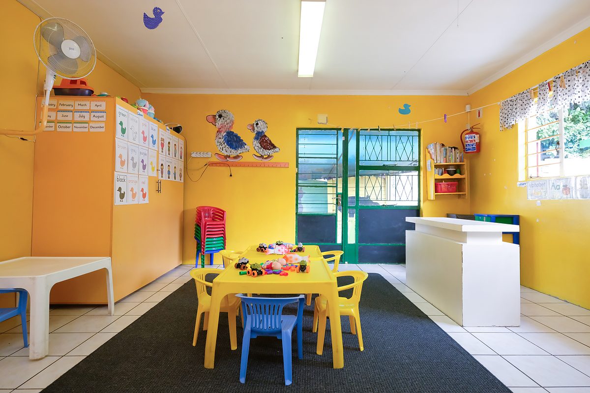 Yellow Class: yellow walls, a low yellow table set with chairs, and charts around the room