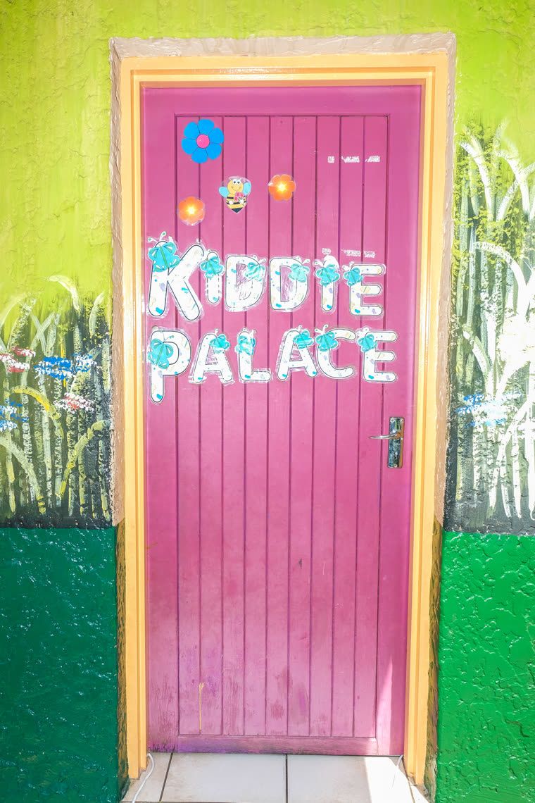 A bright pink door with KIDDIE PALACE painted across it