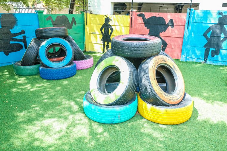 Stacks of painted tyres in blue, yellow and green on the artificial lawn