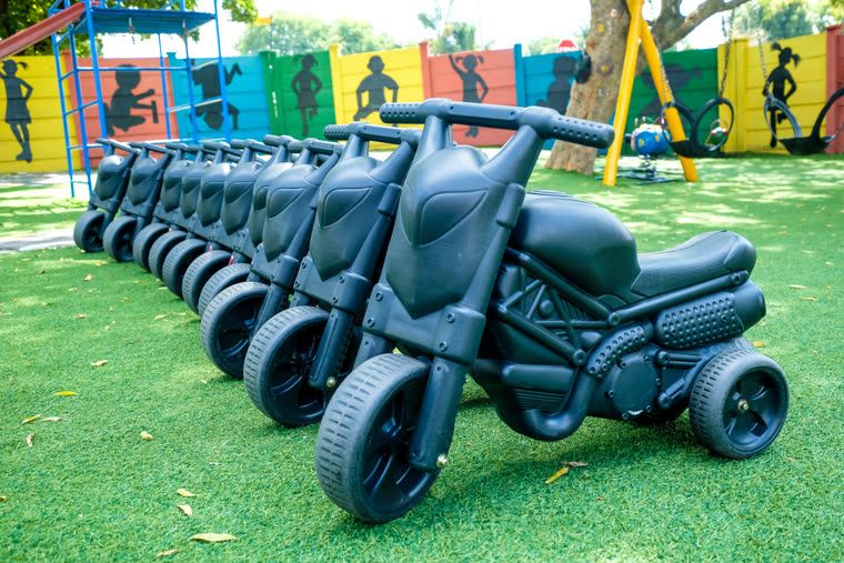 A row of black ride-on motorbikes lined up on the lawn