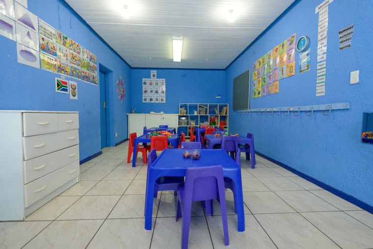 Blue Class: blue walls, low tables and chairs, a bookshelf and wall charts