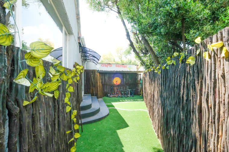 A shaded outdoor corner with a reed screen and artificial lawn